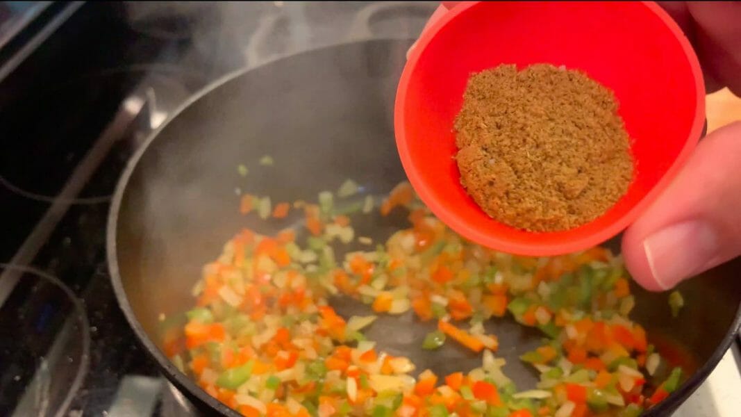 adding seasoning to chili