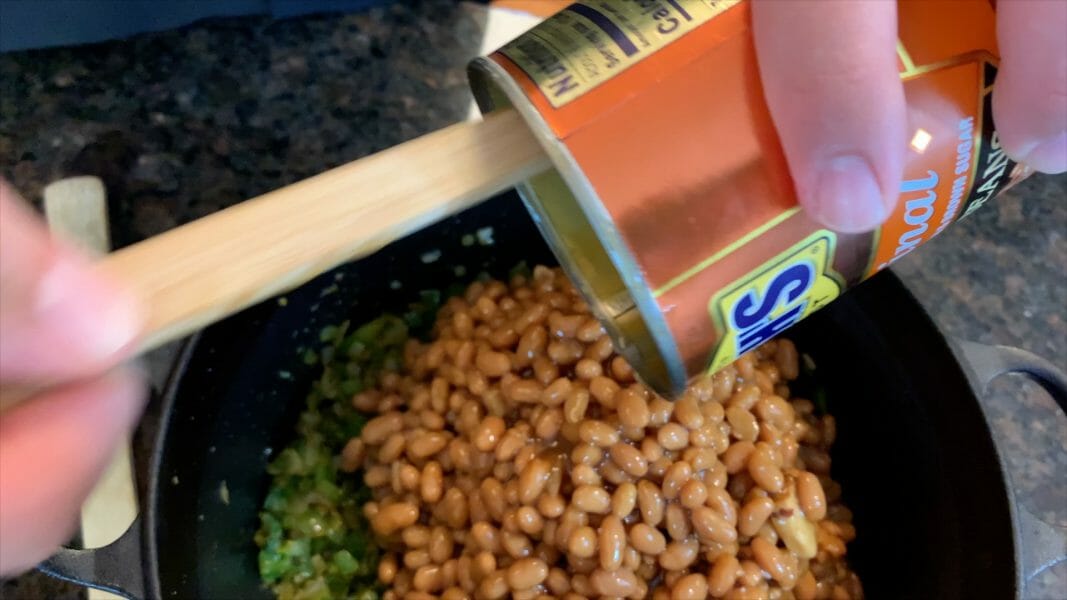 adding baked beans to the pot