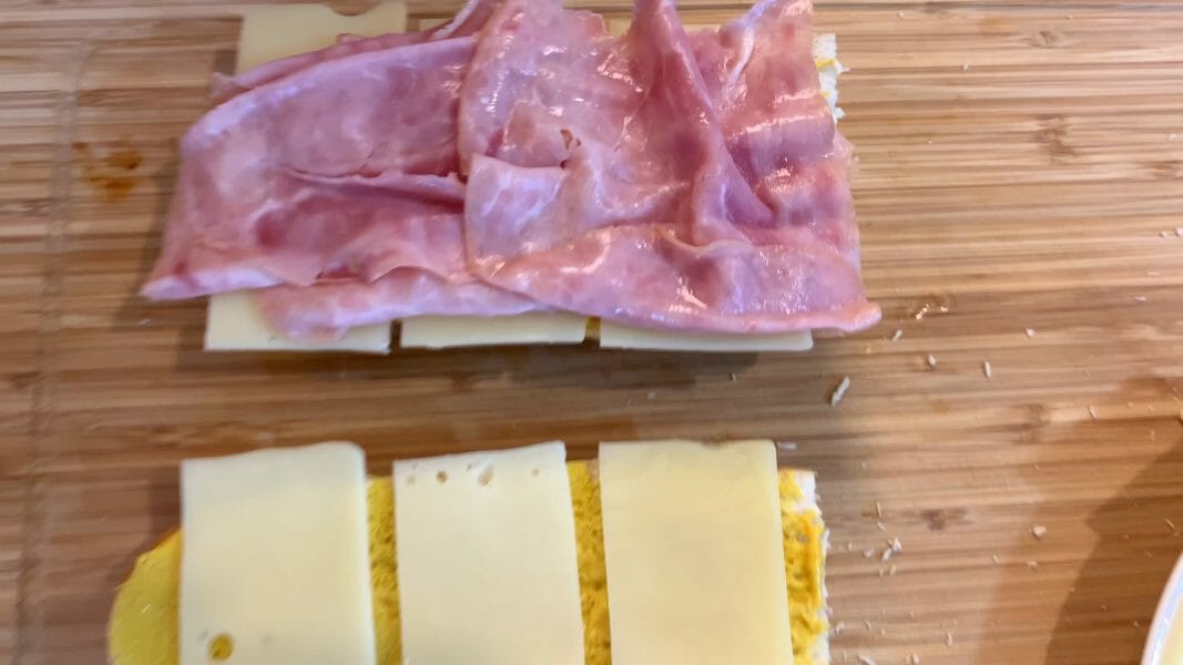 layering swiss cheese and ham on the bread for Cuban sandwich