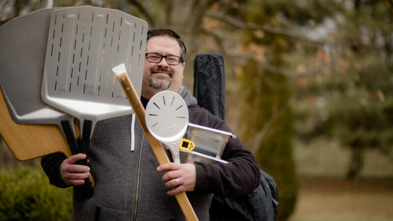 David holding a variety of Ooni pizza oven accessories