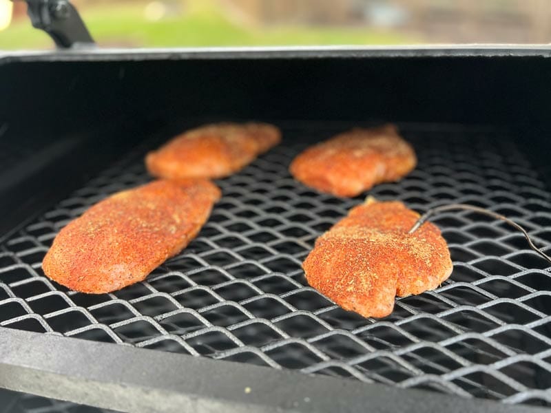 seasoned chicken breasts on the smoker