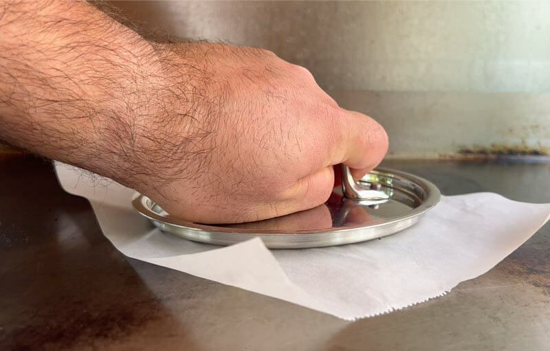 pot lids can be used to smash burgers with the help of parchment paper