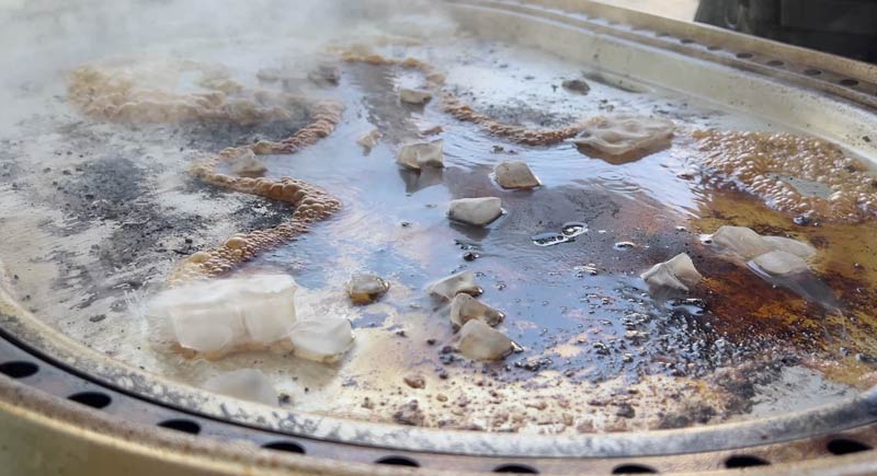 cleaning-with-ice Ice cubes melting on the hot messy surface of the Steelfire Grill to steam clean the food particles loose.