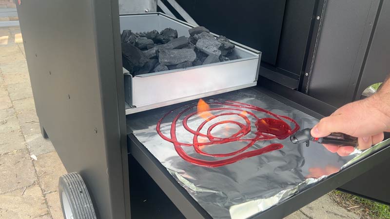 lighting fire starter gel on the ash pan to ignite charcoal in the Hasty Bake Legacy model 131