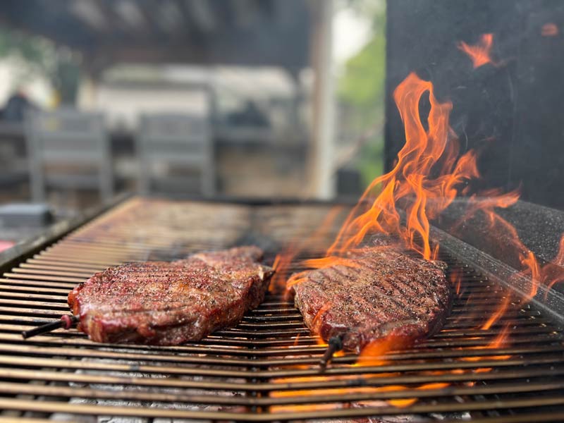ribeye steaks searing over the hot coals in the Hasty Bake Legacy