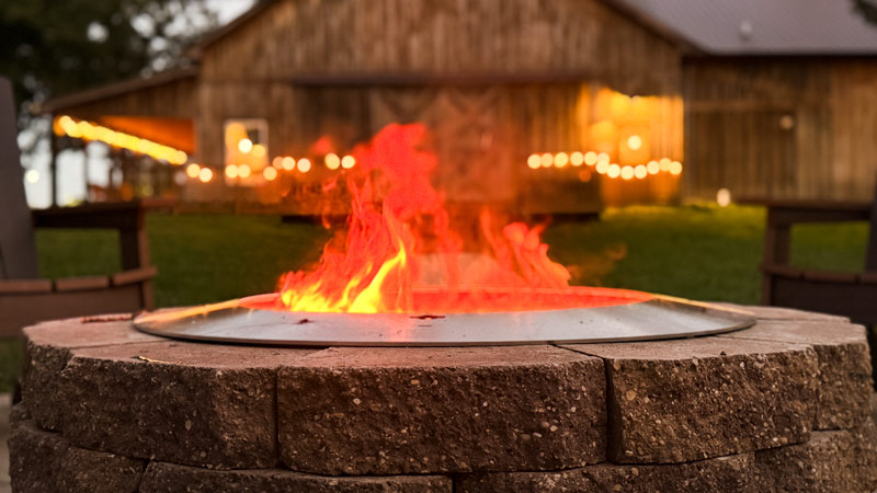 fire burning in the Zentro fire pit at dusk with barn in the background